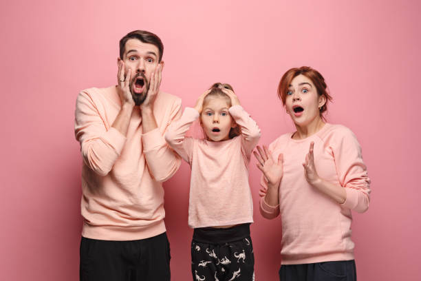 istock Surprised young family looking at camera on pink 881584616
