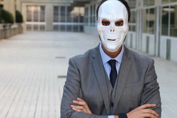 Businessman with arms crossed wearing a horrible mask.