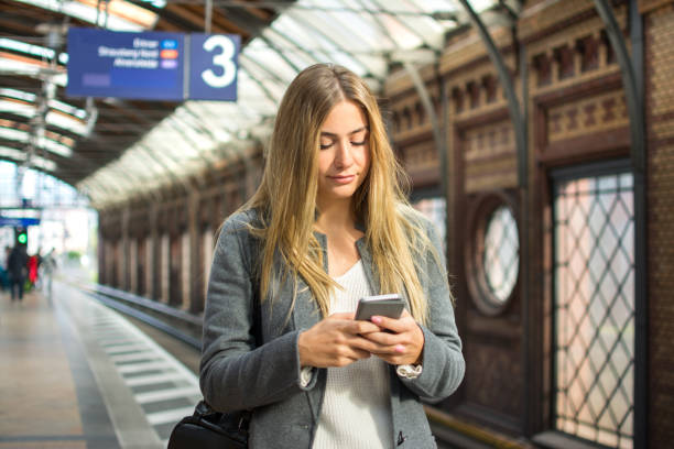 istock Young woman using mobile phone while waiting for train at railway station. 881598260