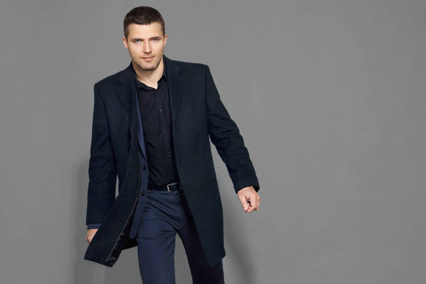 istock guy in a black coat and suit 881598592