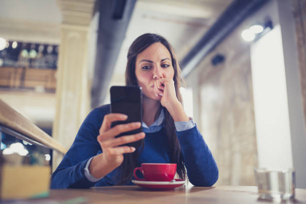 solo. mujer joven preocupada con teléfono inteligente en café - cafe laptop espresso business fotografías e imágenes de stock
