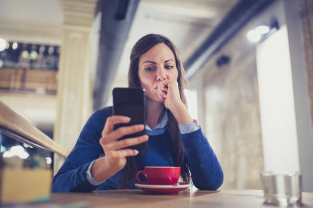 Single. Worried young woman using smart phone in cafe