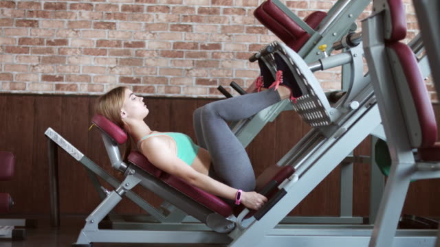 Fitness girl working out on leg press machine