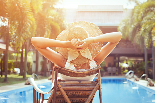 beach holidays and travel, relaxation in luxurious hotel, young happy woman tourist resting near swimming pool