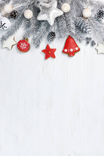 istock silver christmas fir tree branches with decorations and gingerbreads on white wooden background 881609436