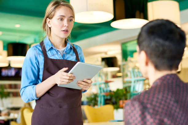 Young Waitress Taking Orders in Cafe Portrait of young cafe waitress  wearing apron taking order from client using digital tablet, copy space first job photos stock pictures, royalty-free photos & images