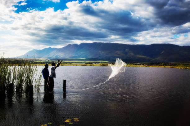 Men throw a fishing net into the water
