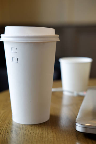 istock White disposable paper cup with plastic lid on wood table 881620040