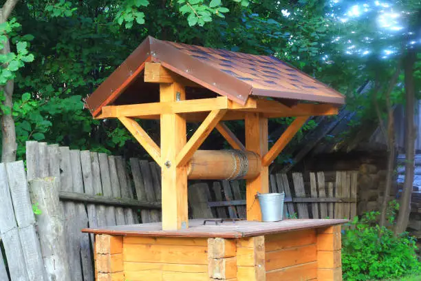 A village well made of wood with a galvanized bucket on a chain