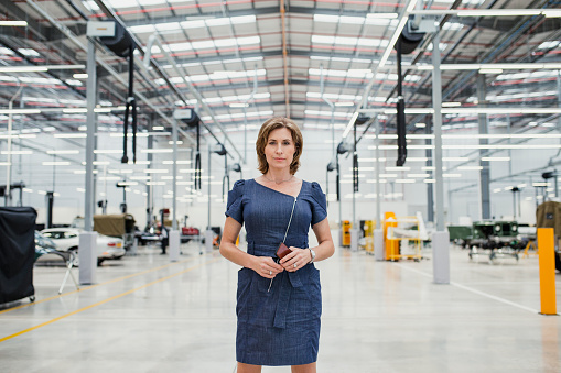 Portrait of a female CEO standing in a high-end car garage.