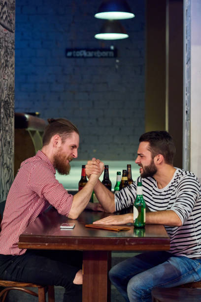 two men armwrestling in bar - arm wrestling imagens e fotografias de stock