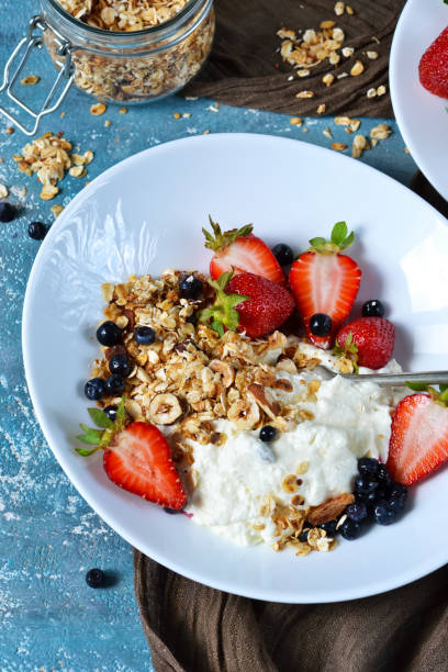 istock Good morning! Breakfast with yoghurt, granola and strawberries on a blue, concrete background. 881641796