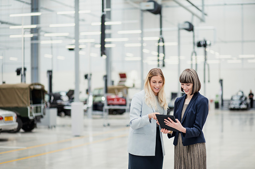 Two female professionals having a relaxed meeting while strolling through a high-end garage.