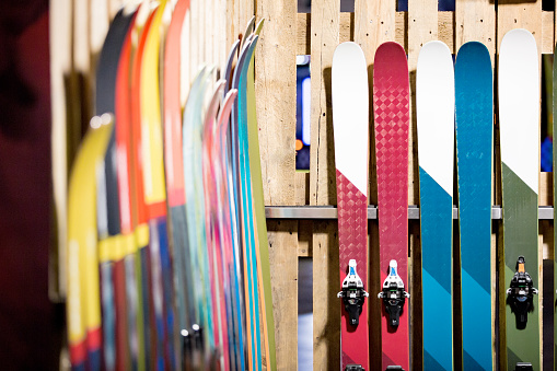 Ski shop sale. Rows of  colourful skis on wooden wall.