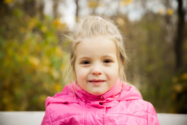 istock Little playful girl in a pink jacket 881698928