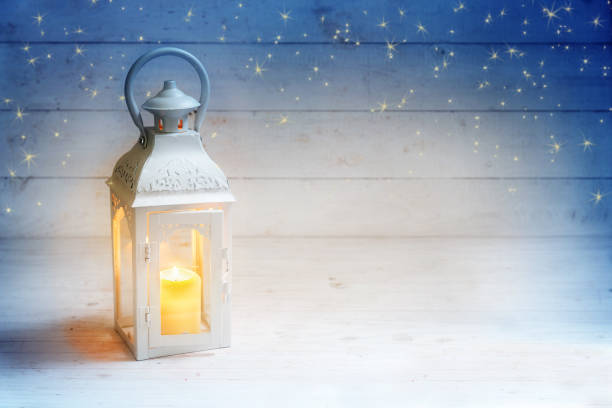 istock Christmas background with a lantern and burning candle light on rustic white wood, blue sky with stars, copy space 881703308