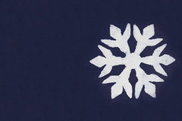 istock One white snowflake painted with paint through a stencil on a dark blue background. Copy space. 881712614