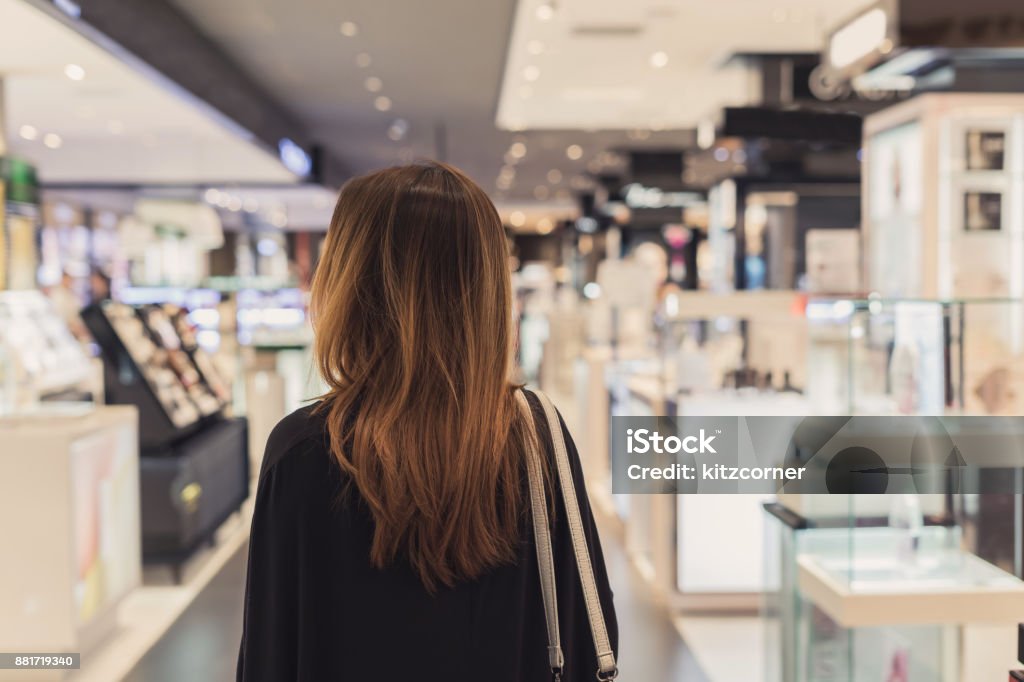 Young asian woman walking in cosmetics department at the mall Retail Stock Photo