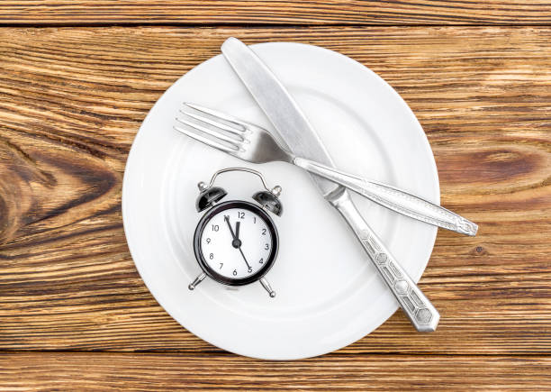 istock Alarm clock with fork, knife and plate on the table. Top view. Time to eat. 881764034