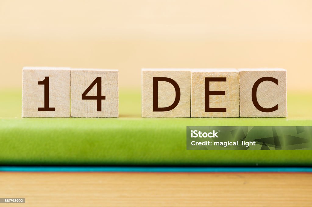 Wooden cube shape calendar for DEC 14 on green book, table. 2018 Stock Photo