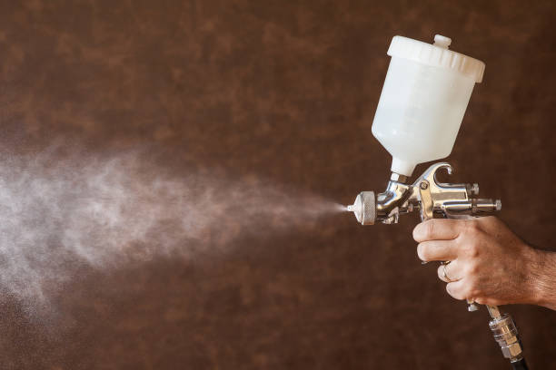 istock Close up of a spray paint gun with brown background 881817480