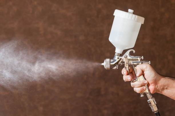 istock Close up of a spray paint gun with brown background 881817502