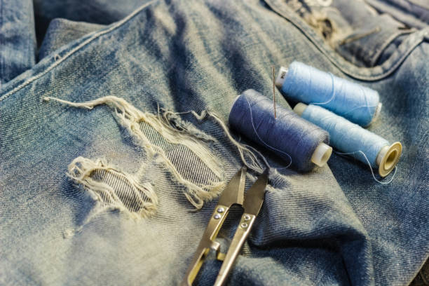 istock On the sewing table are blue jeans with threads and scissors. Close-up. 881817742