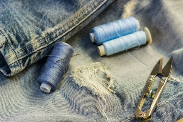 istock On the sewing table are blue jeans with threads and scissors. Close-up. 881817778