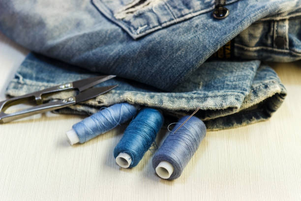istock On the sewing table are blue jeans with threads and scissors. Close-up. 881817840