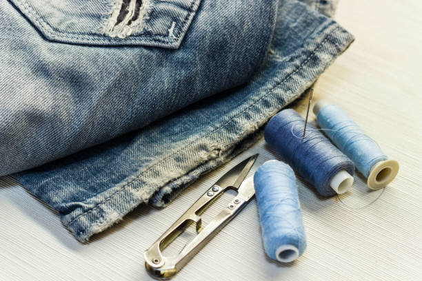 istock On the sewing table are blue jeans with threads and scissors. Close-up. 881817864