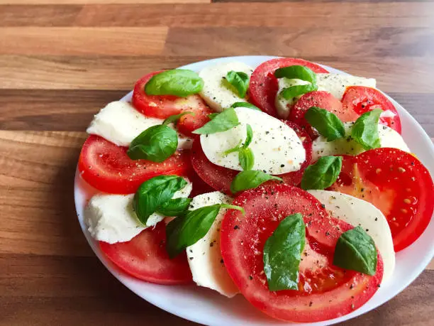 Photo of healthy salad with mozzarella, tomato and green basil
