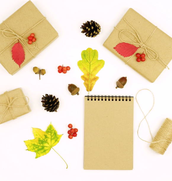 Autumn composition with leaves, gifts packed in craft paper, notepad for text on white background.Top view. Flat lay. Copy space