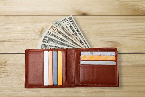 Wallet with cards and money on wooden background