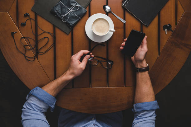 istock man with eyeglasses, smartphone and coffee 881857572