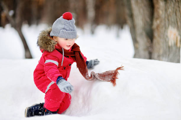 istock Little boy in red winter clothes having fun with fresh snow 881865994