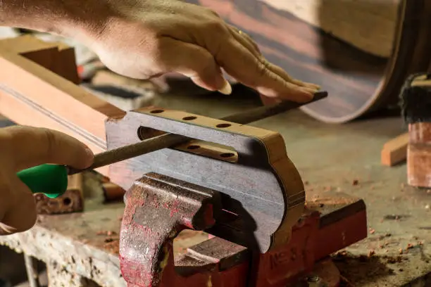 Photo of Luthier making a peghead of classical guitar