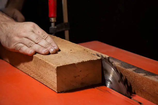 Photo of A craftsman cutting a plank of wood with circular table saw