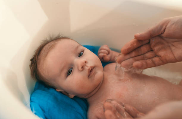 istock Unrecognizable father bathing her son in white small plastic bat. 881886114