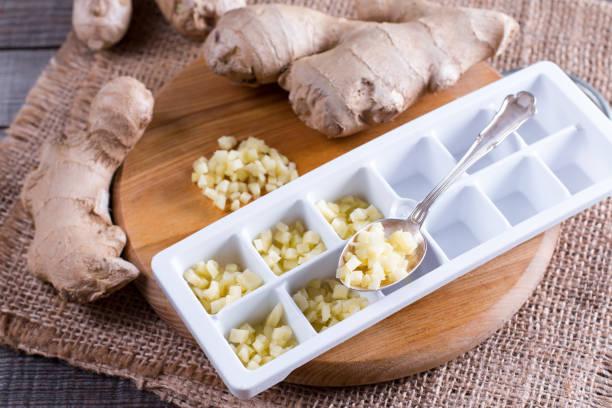 istock Pieces of ginger in a container for freezing ice cubes on a board 881887302
