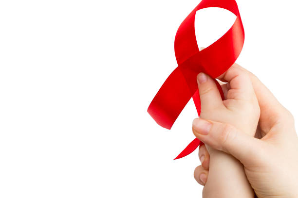 istock Aids red ribbon on woman's and child's hands support for World aids day 881890308