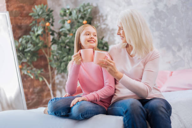 istock Joyful nice grandmother and granddaughter cheering with cups 881900962