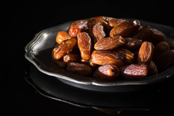 istock Sweet dessert dried date in old tin bowl, low key, dark theme, on black background with reflection 881912346