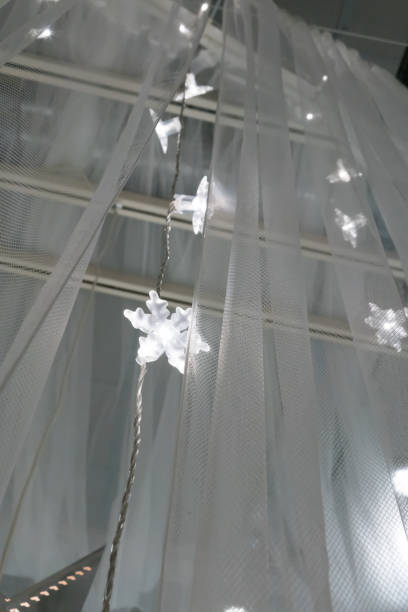 istock Illuminated LED icicle light against sheer fabric background for winter or Christmas decoration. 881952784