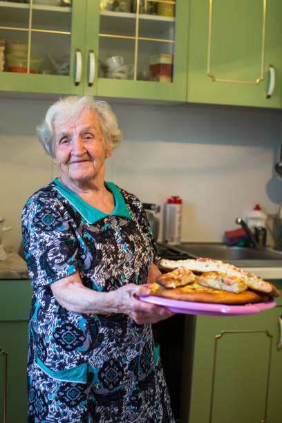 istock Elderly woman in the kitchen with a pie in his hands. 881983752