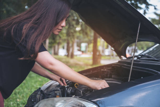 istock Woman try to fixing broken old car with outdoor background 881984342