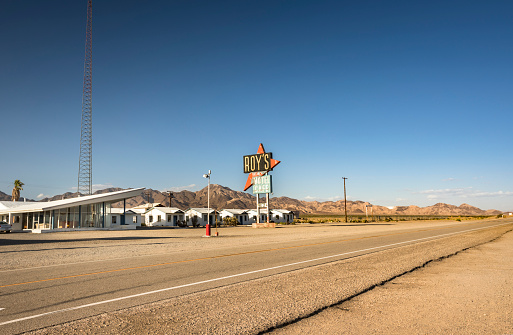 Amboy: Road alongside Roy's Motel and Café.  Amboy is an unincorporated community in San Bernardino County, in California's Mojave Desert, west of Needles on historic Route 66.  Prior to 2015, the town's business district contains a post office, a historic restaurant-motel, and a Route 66 tourist shop.
