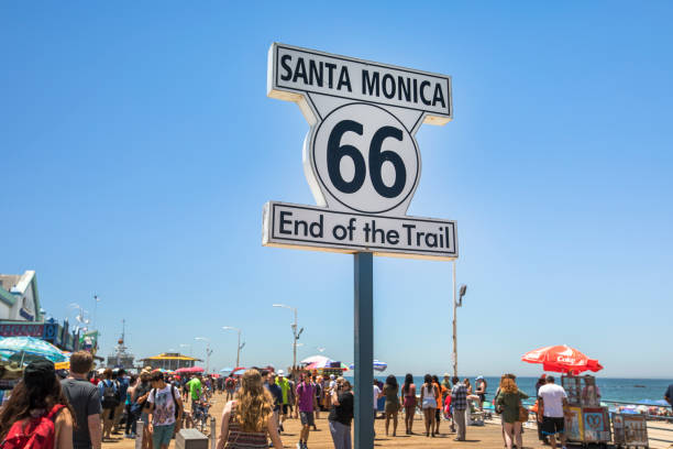 Santa Monica:  Road marker of the final destination ending point of Route 66 in Santa Monica California USA.  Santa Monica Pier and amusement park in Los Angeles California USA.  The pier contains Pacific Park, a family amusement park with its one-of-a-kind, state-of-the-art, solar panelled Ferris wheel.