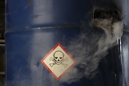 Gas tóxico venenoso y fugas de barril de acero azul, signo de material tóxico en la superficie del barril dañado photo