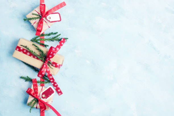 istock Flat lay top view three christmas gift boxes in craft paper with red ribbons on light blue background 882029752