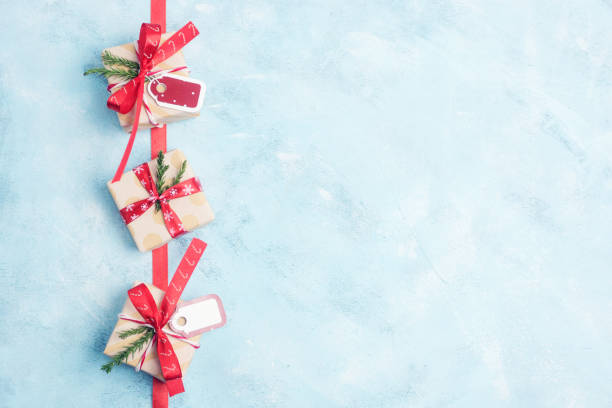 istock Flat lay top view three christmas gift boxes in craft paper with red ribbons on light blue background 882029838